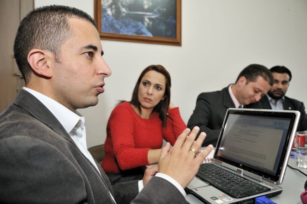 A man explains something in front of a laptop